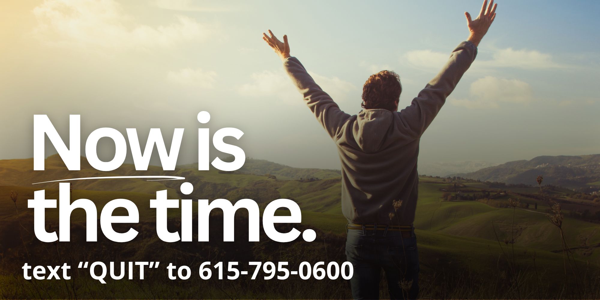 Person standing on a hillside with arms raised. Text reads: Now is the time. text QUIT to 615-795-0600.